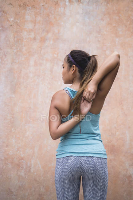 Young asian sporty woman making stretching, rear view — Stock Photo