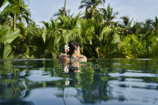Vue arrière de jeune asiatique femme relaxant dans une piscine — Photo de stock