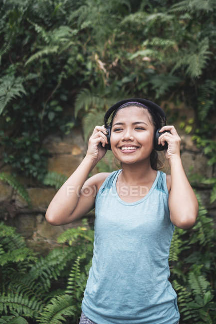 Jovem asiático desportivo mulher vestindo fones de ouvido no parque — Fotografia de Stock