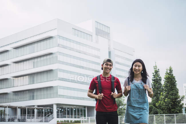 Joven asiático universidad estudiantes de pie contra campus - foto de stock