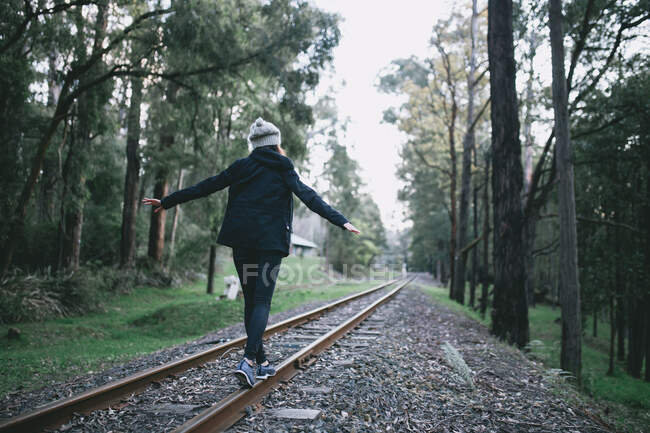 Jovem senhora caminhando e explorando a trilha ferroviária — Fotografia de Stock