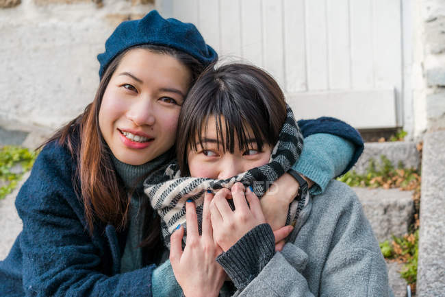 Молоді випадкові азіатські дівчата обіймаються і позують на камеру — стокове фото