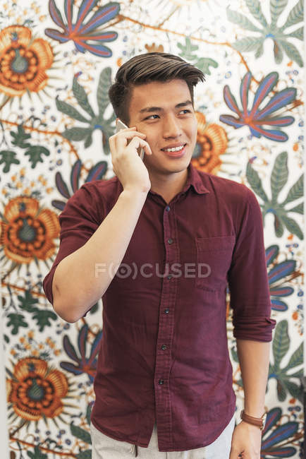 Молодий азіатський бізнесмен розмовляє на смартфоні в сучасному офісі — стокове фото