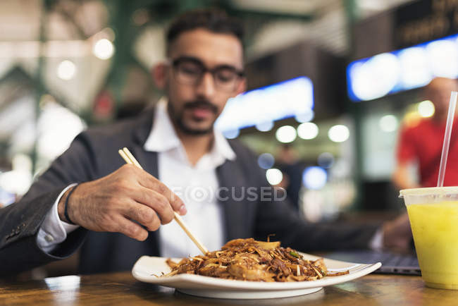 Handsome indian business man eating in cafe — Stock Photo