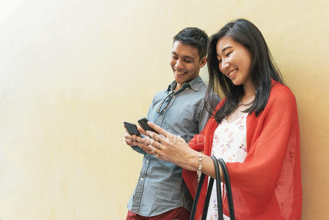 Молодая счастливая азиатская пара с помощью смартфонов в Чайнатауне — стоковое фото