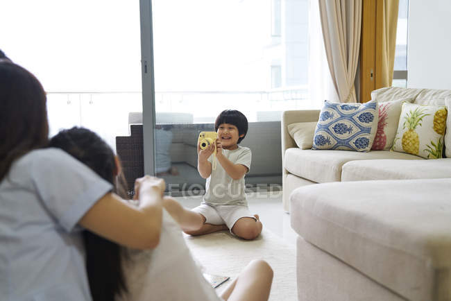 Happy young asian family together, boy photographing family — Stock Photo