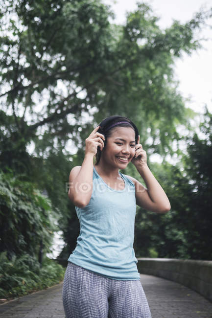 Молодая азиатская спортсменка с наушниками в парке — стоковое фото
