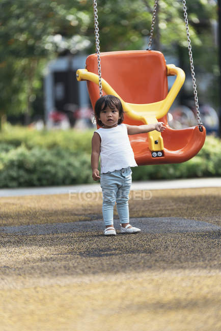Милая очаровательная азиатская маленькая девочка на качелях на детской площадке — стоковое фото