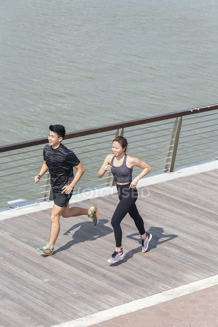 Sportliches junges Paar läuft auf Seebrücke — Stockfoto