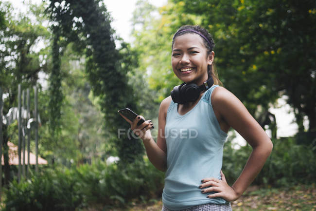 Giovane asiatica donna sportiva utilizzando smartphone nel parco — Foto stock