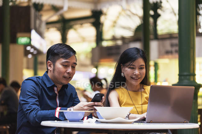 Щаслива азіатська молода пара разом використовує смартфон у кафе — стокове фото