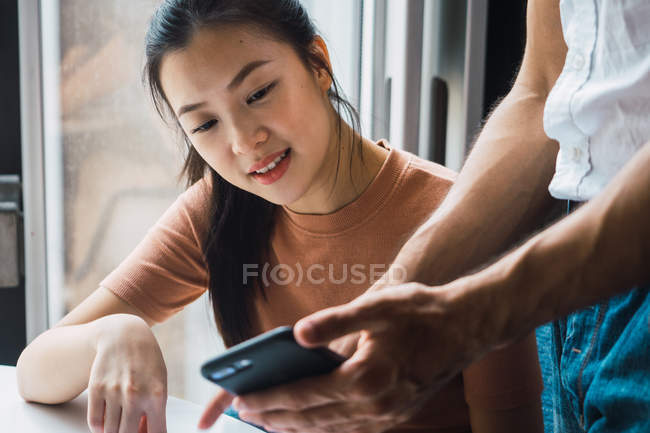 Junge erfolgreiche asiatische Geschäftsfrau schaut aufs Smartphone — Stockfoto