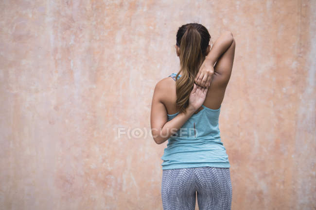 Вид сзади молодой азиатской спортсменки, делающей растяжку — стоковое фото