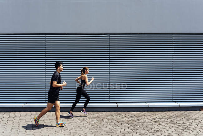 Sportliches junges Paar läuft gemeinsam auf Stadtstraße — Stockfoto