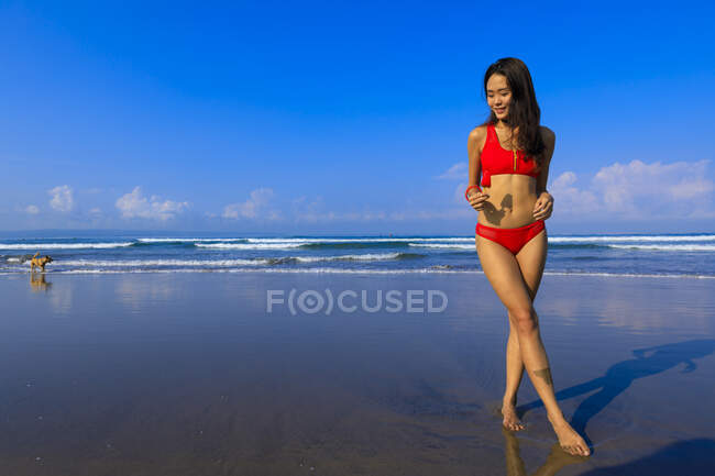 Asiatische Mädchen auf einem Strand im Bikini mit einem Eis in der Hand. — Stockfoto