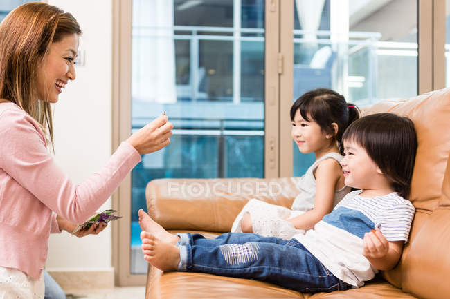 Side view of mother feeding children at home — Stock Photo