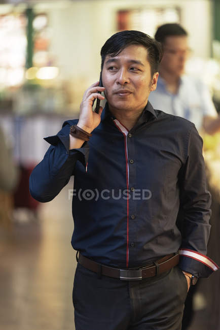 Happy asian young man talking on smartphone — Stock Photo