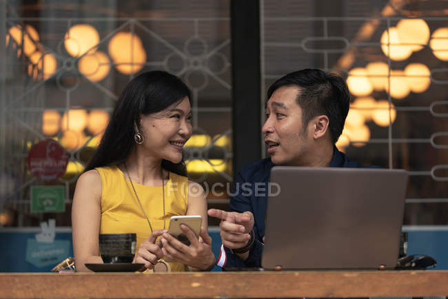 Счастливая азиатская молодая пара вместе с помощью ноутбука в кафе — стоковое фото