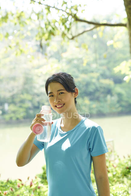 Femme hydratante après avoir travaillé dans les jardins botaniques, Singapour — Photo de stock