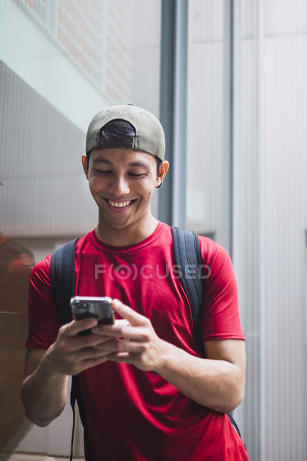 Молодой студент азиатского колледжа, использующий смартфон — стоковое фото