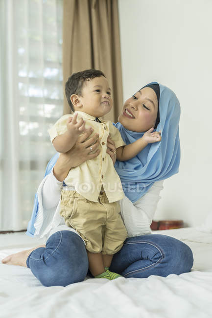 Молода азіатська мусульманська мати і дитина розважаються вдома — стокове фото