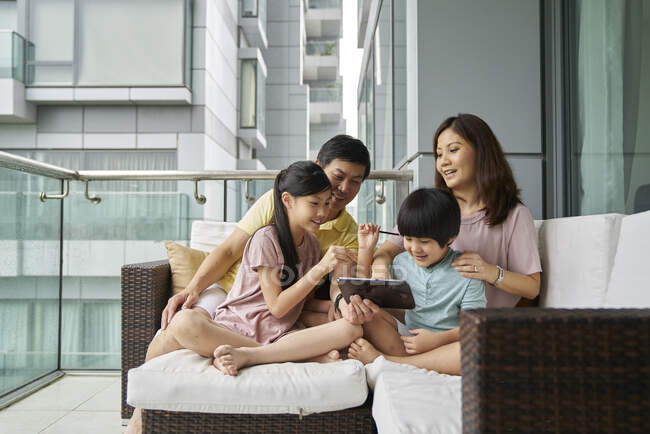 Feliz joven asiático familia juntos usando digital tablet en casa - foto de stock