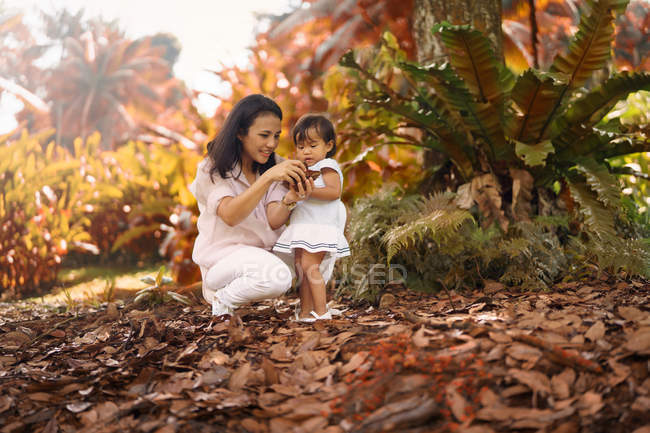 Jeune mère asiatique avec mignonne petite fille dans le parc — Photo de stock