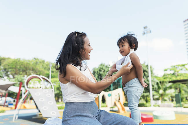 Милий чарівний азіатський маленька дівчинка на дитячому майданчику з матір'ю — стокове фото