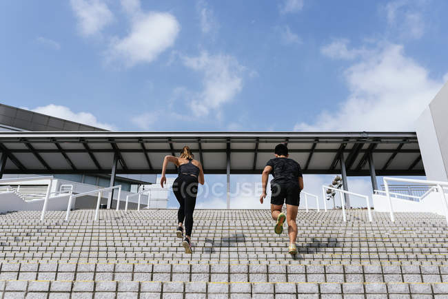 Молодая спортивная пара, бегающая вместе по лестнице, вид сзади — стоковое фото