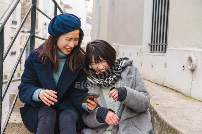 Young casual asian girls using smartphone in city — Stock Photo