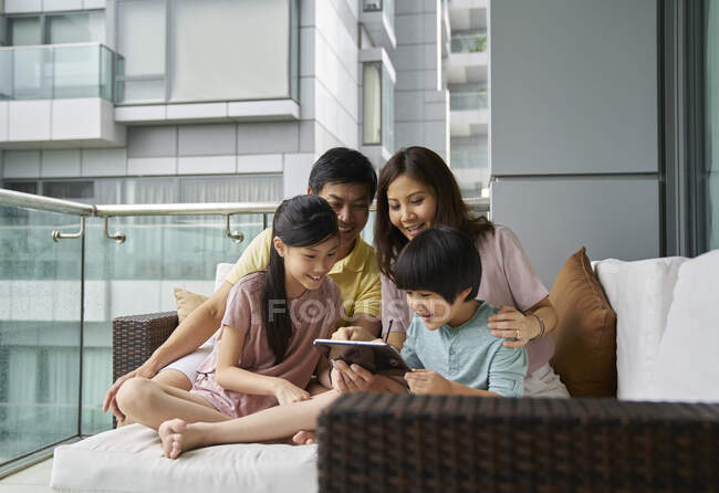 Happy young asian family together using digital tablet at home — Stock Photo