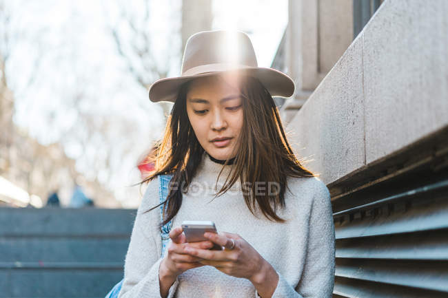 Junge attraktive asiatische Frau mit Smartphone auf Treppen — Stockfoto