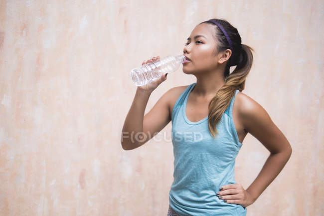 Молода азіатська спортивна жінка п'є воду — стокове фото