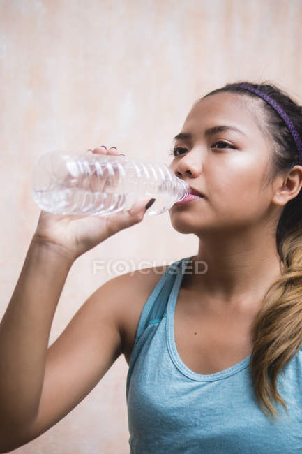 Junge asiatische sportliche Frau trinkt Wasser — Stockfoto
