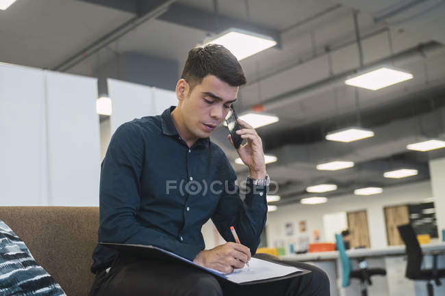 Успішний бізнесмен розмовляє по телефону в сучасному офісі — стокове фото