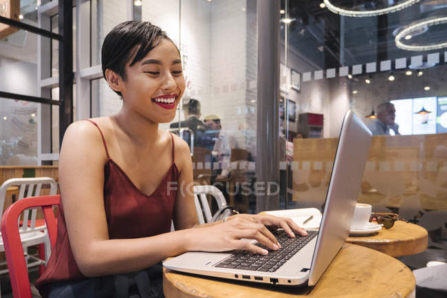Giovane attraente asiatico donna utilizzando laptop in caffè — Foto stock