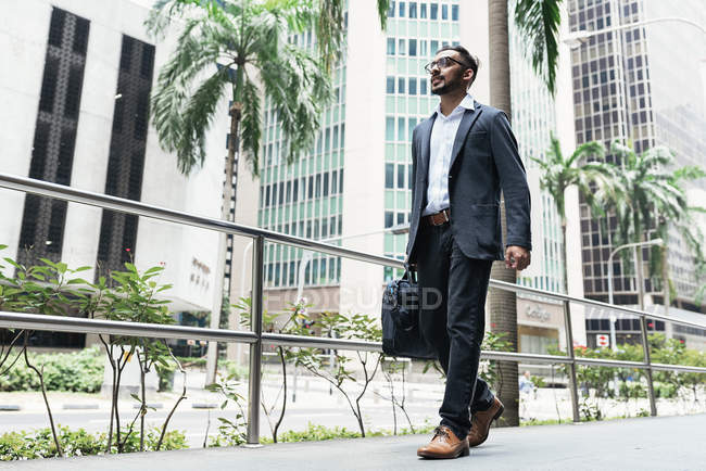 Schöner indischer Geschäftsmann läuft mit Koffer auf der Straße — Stockfoto