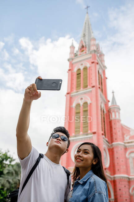 Joven pareja vietnamita tomando selfie frente a la iglesia Tan Dinh, Saigón. - foto de stock