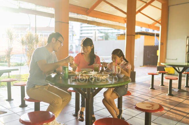 Молода азіатська сім'я разом їсть у кафе — стокове фото