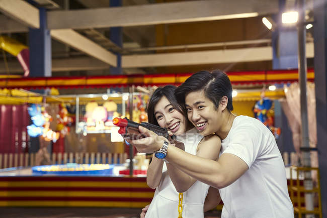 Couple playing a shooting game at a carnival to win prizes in Singapore — Stock Photo