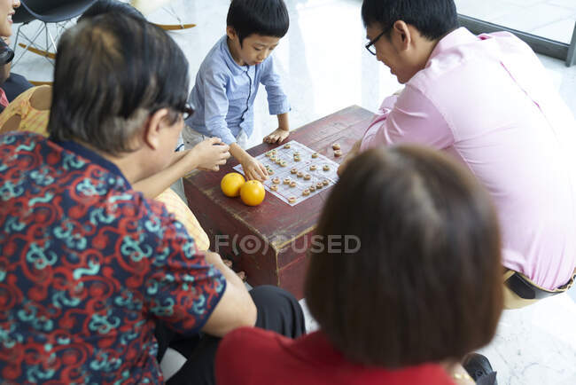 Familia asiática feliz pasar tiempo juntos y jugando juego de mesa - foto de stock