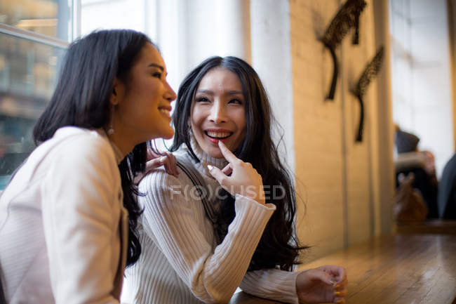 Sonrientes mujeres jóvenes en la cafetería juntas - foto de stock