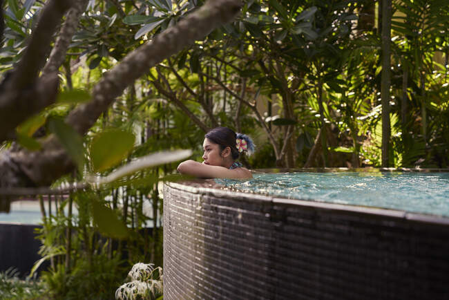 Seitenansicht einer jungen asiatischen Frau, die sich in einem Pool entspannt — Stockfoto