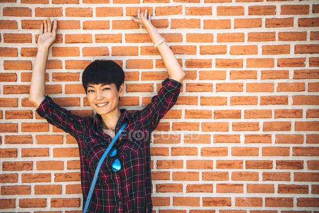 Belle femme chinoise posant pour caméra contre un mur de briques — Photo de stock