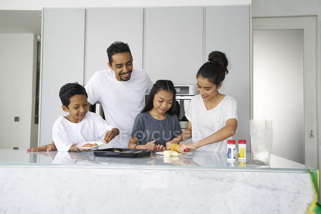 Familia asiática joven celebrando Hari Raya juntos en casa y cocinar platos tradicionales - foto de stock