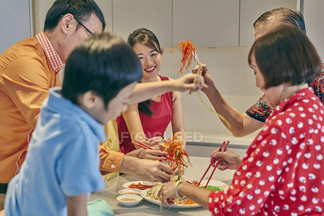 Familia asiática feliz comiendo juntos en la mesa en año nuevo chino - foto de stock