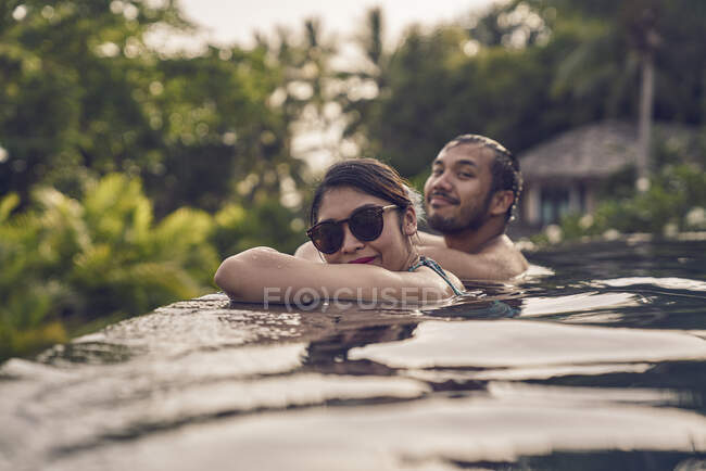 Jeune couple asiatique relaxant dans une piscine — Photo de stock
