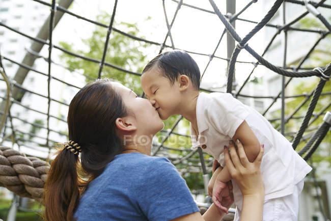 Madre vinculación con el hijo en el patio de recreo - foto de stock