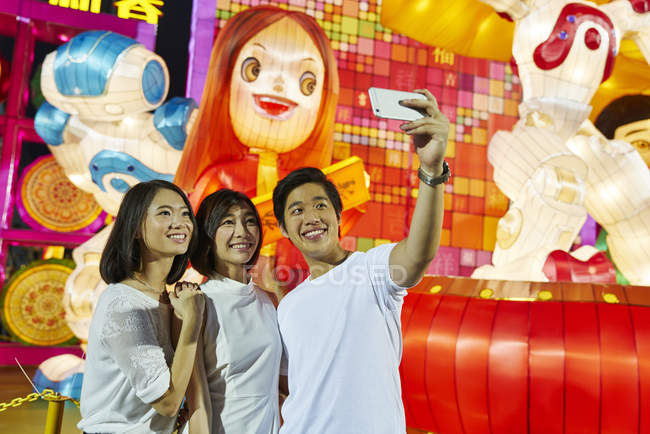 Young asian friends having fun at Chinese New Year festival and taking selfie — Stock Photo