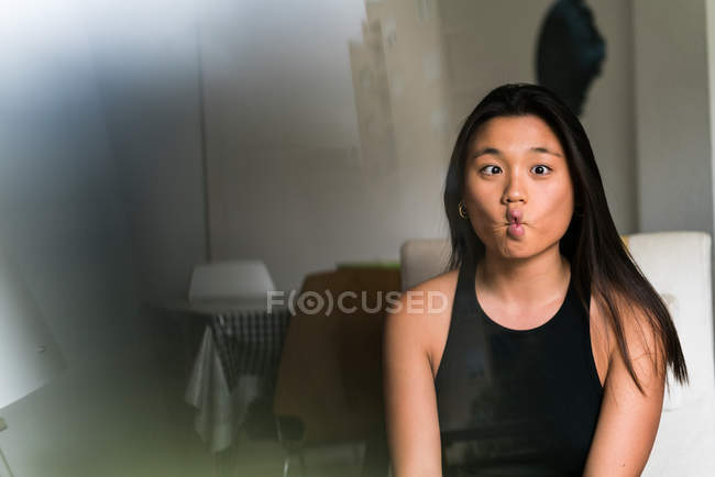Chinese woman making funny faces at home — Stock Photo